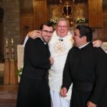 Br. Jonathon, Fr. Jim, and Br. Jorge hugging at the brothers' Final Vows ceremony