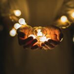Outstretched hands holding Christmas lights