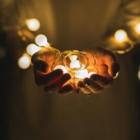 Outstretched hands holding Christmas lights