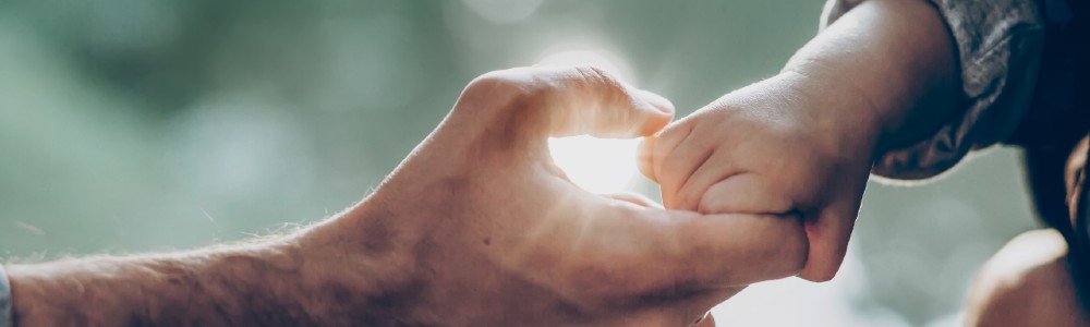 The hand of a young child holding their father's hand