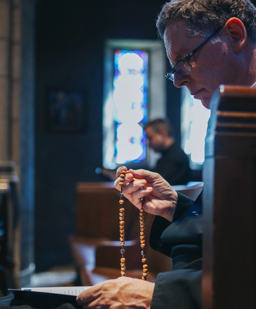 OMV priest praying the rosary in church